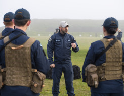 A Royal New Zealand Air Force airman speaks to a group of airmen during training at the range. The day is very misty and wet.