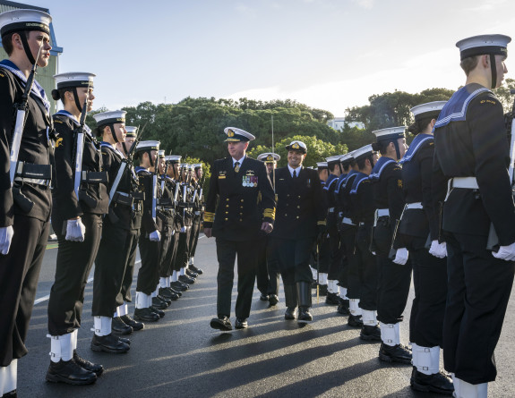 VADM Mark Hammond walks in between two ranks of Navy personnel that are standing to attention. 