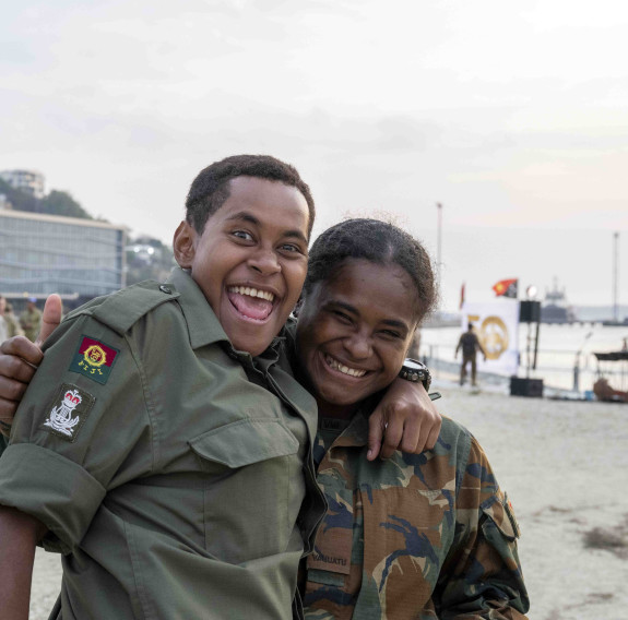 Two personnel from the Papua New Guinea Defence Force, arm-in-arm smile for the camera.