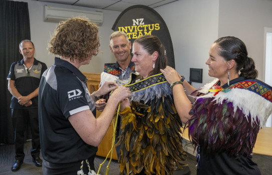 Tracey Dender is presented with the Invictus kahu huruhuru Matariki by Head of Mission Major General Rose King and NZ Invictus Team Co-Captains Flight Sergeant Stacey Adam and Major Soren Hall